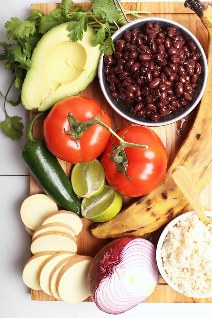 Tomatoes, beans, onions, and plantains on a wooden platter