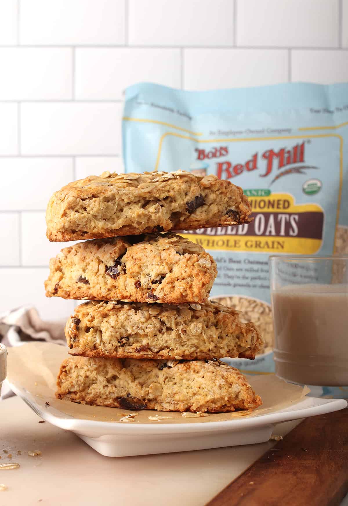 Stack of finished scones on a white plate with a glass of milk in the background. 