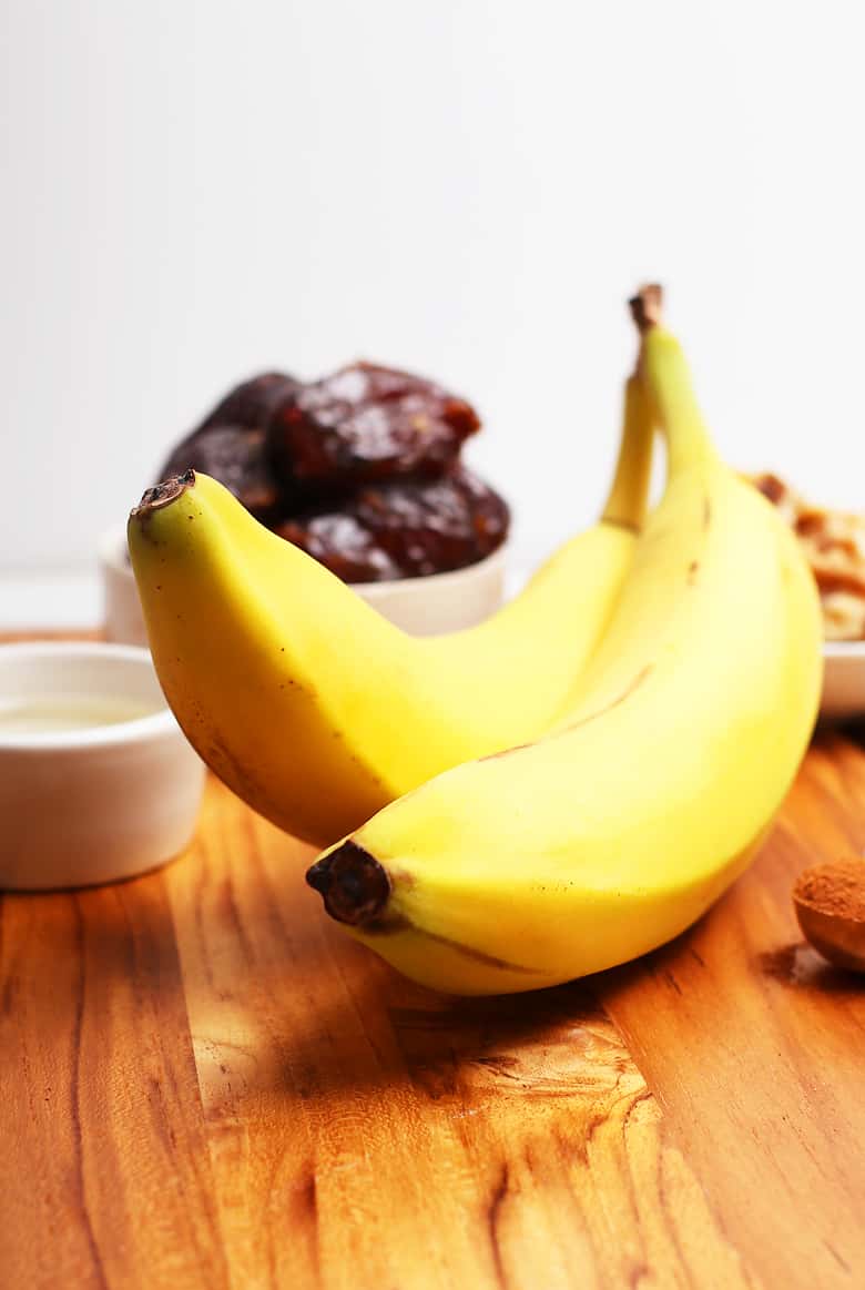 Two bananas on a wooden cutting board