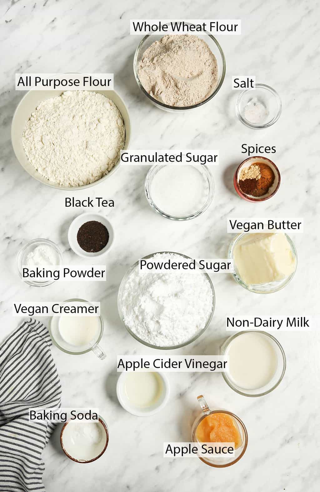 All the ingredients for vegan scones measured out and placed on a marble countertop. 
