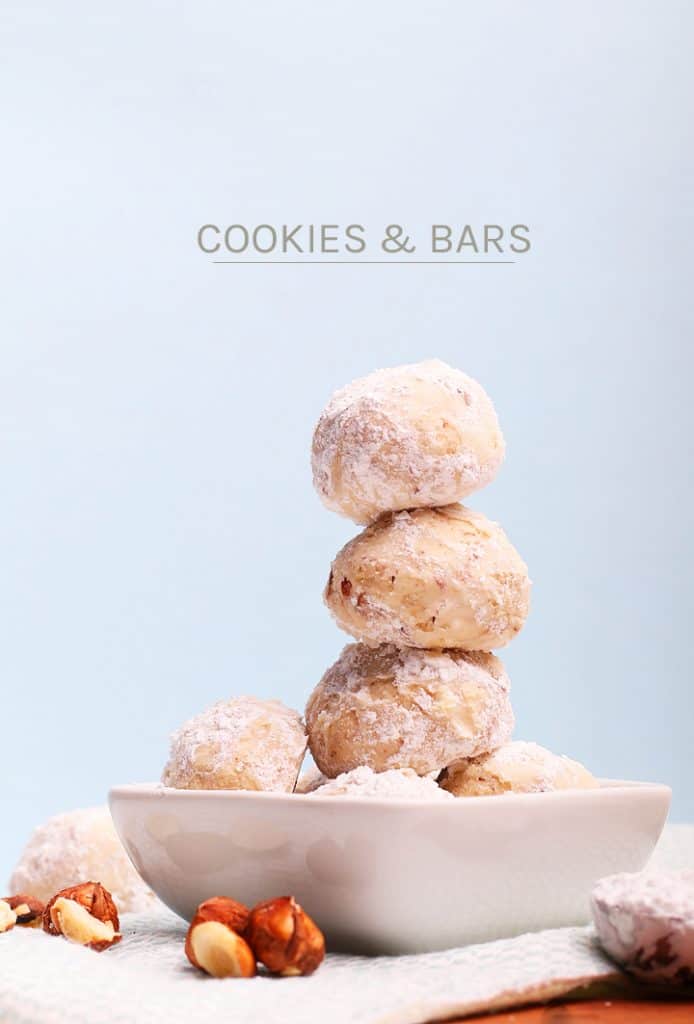 Stack of snowball cookies in a white bowl. 