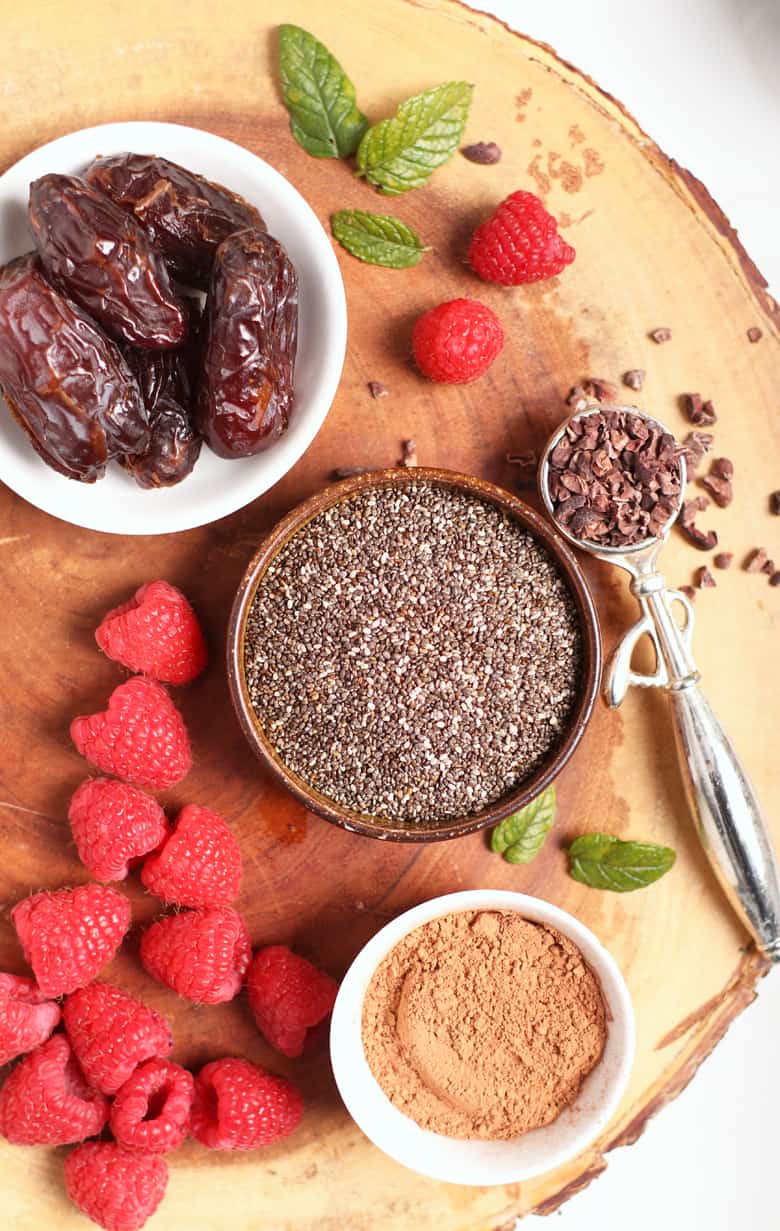 Chia seeds, dates, and raspberries on wooden board