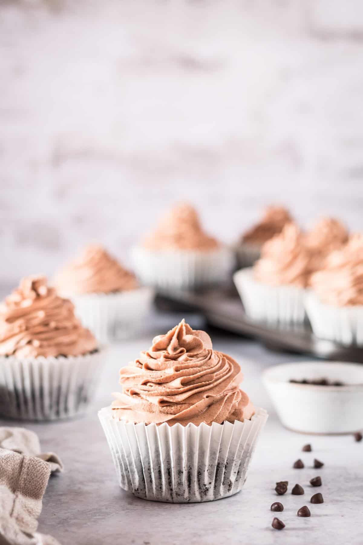 Finished chocolate cupcake in a white cupcake holder on a marble background.