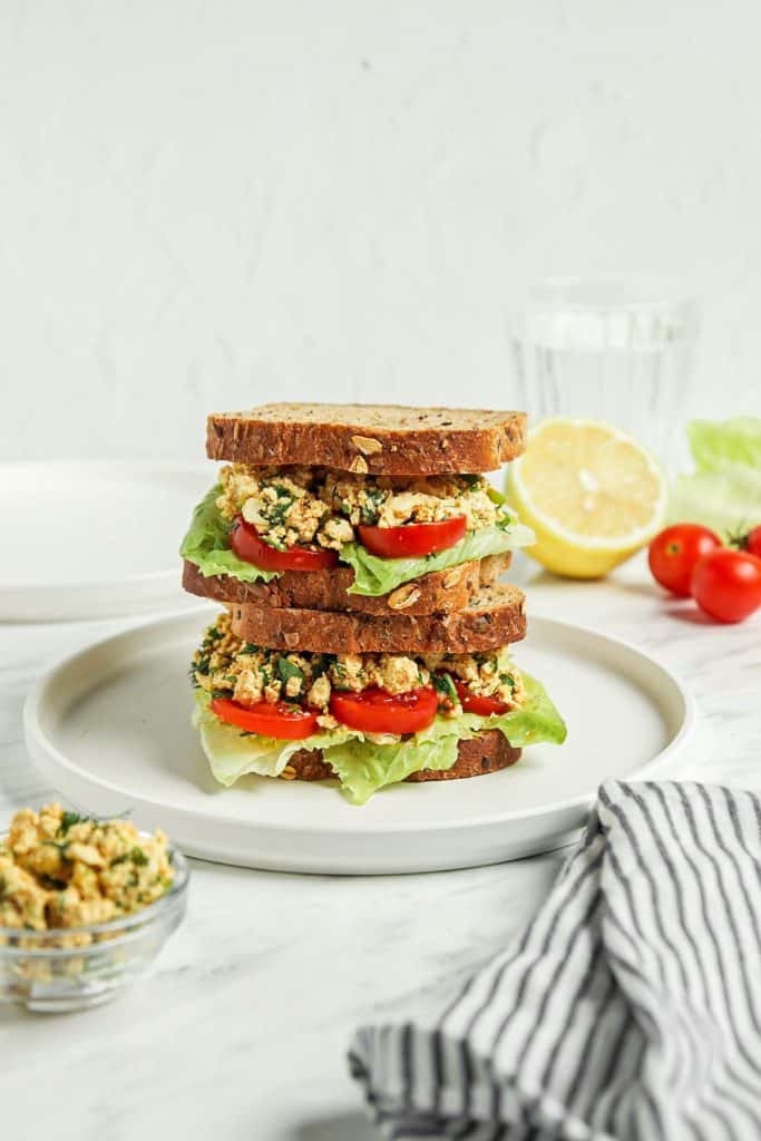 Stacked vegan egg salad sandwich with veggies and yummy tofu filling