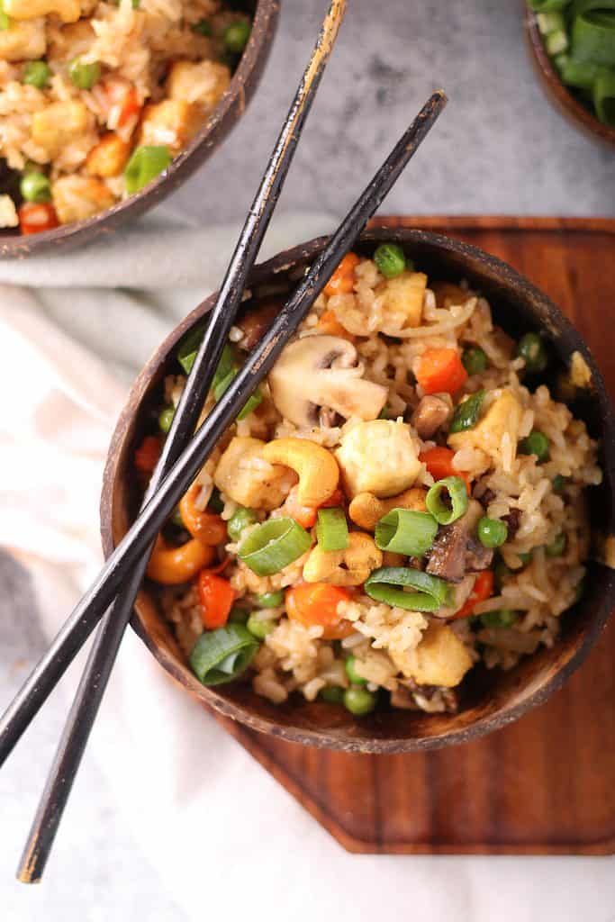 Vegan tofu fried rice in a wooden bowl with chopsticks