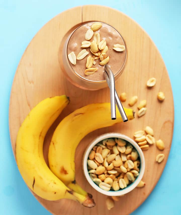 Chocolate smoothie on a wooden board with bananas and peanuts