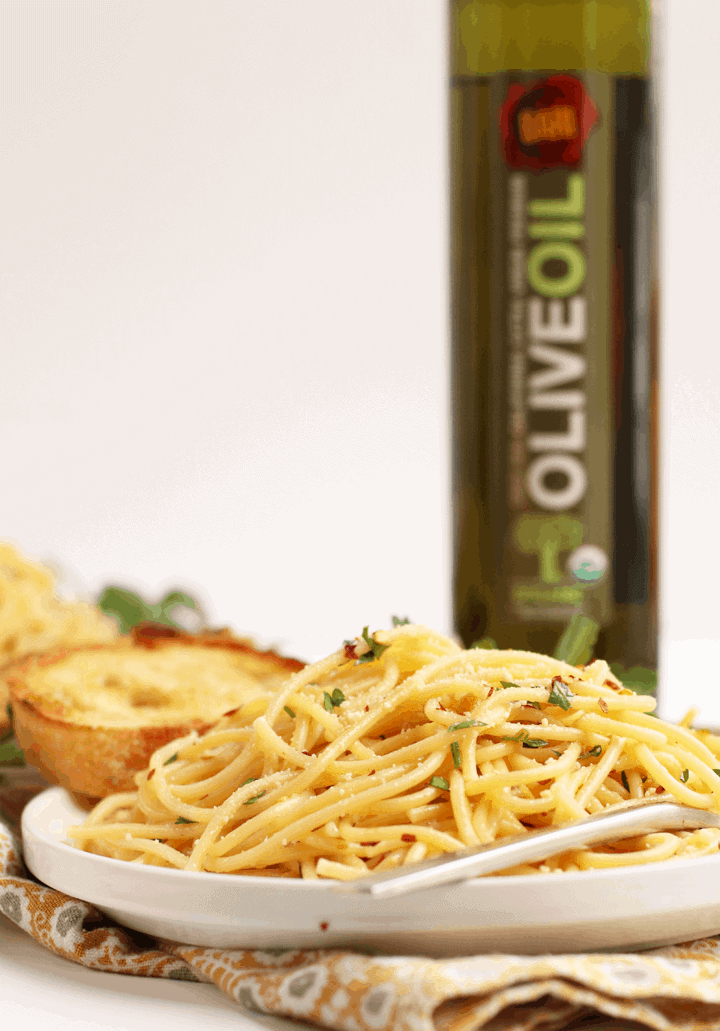 Plate of pasta next to a jar of olive oil