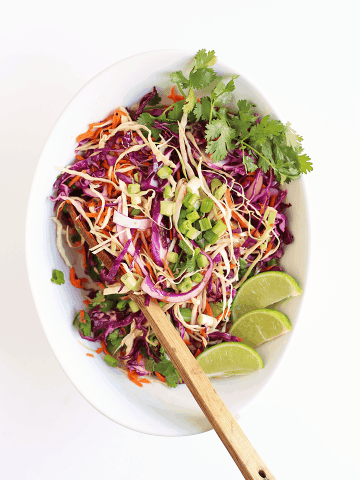 Shredded cabbage in a white bowl with a wooden spoon