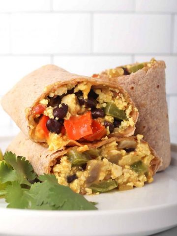 Finished breakfast burrito cut in half and stacked on a white plate