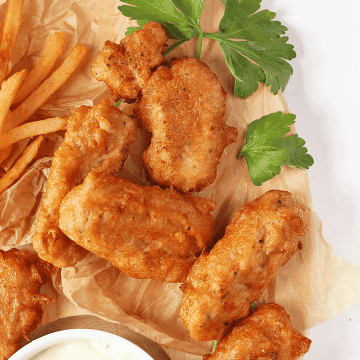 Finished Vegan Fish Sticks on a wooden platter with fries