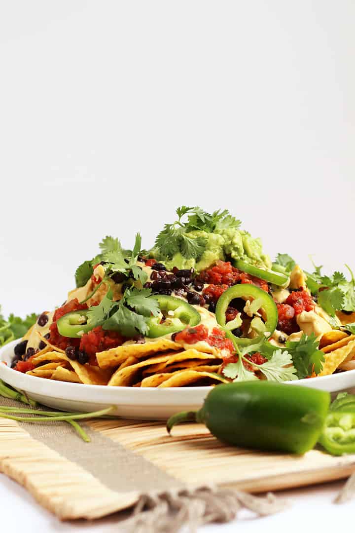 Vegan Nachos stacked high on a white plate