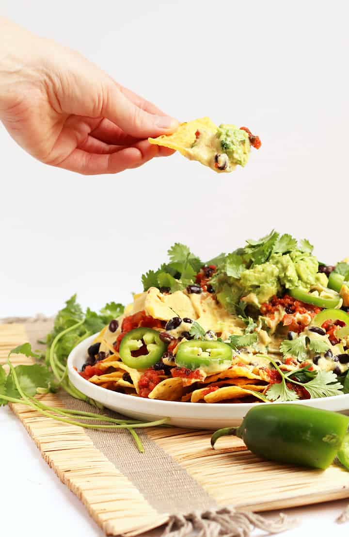 Tortilla chip topped with cheese sauce and guacamole