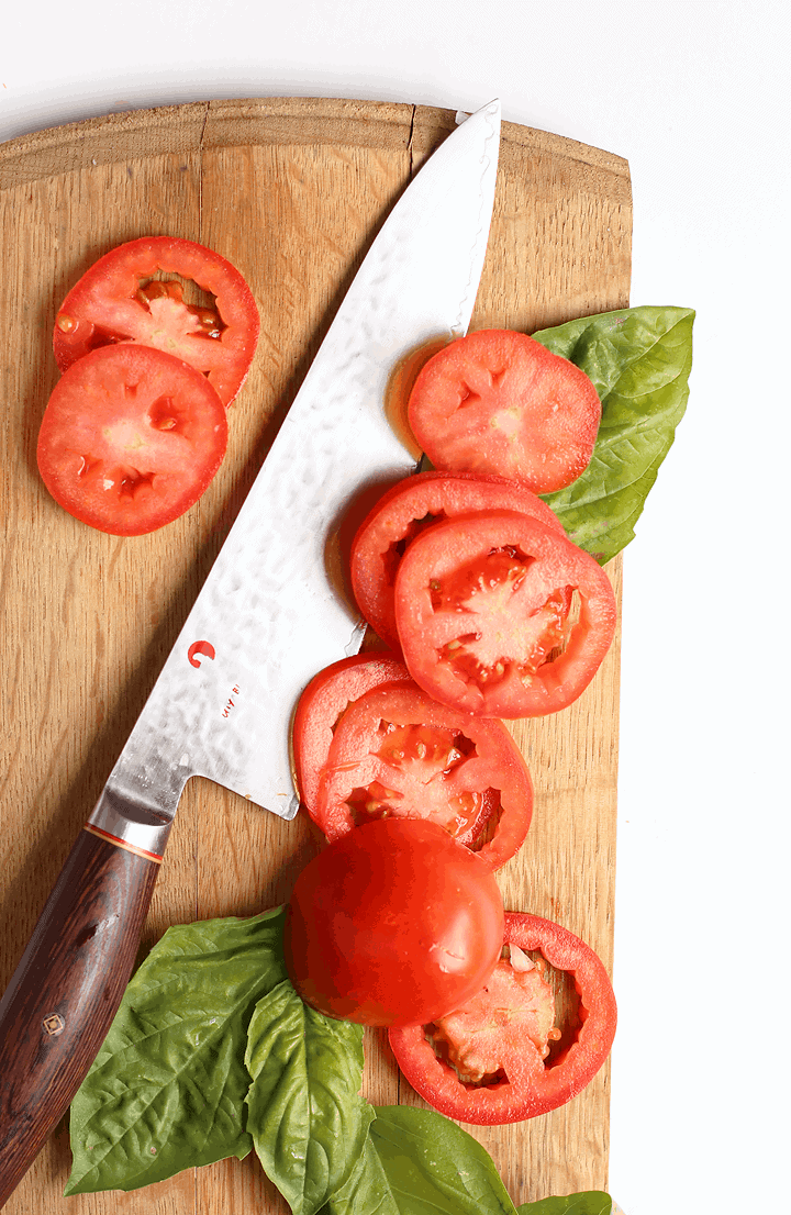 Sliced tomatoes and fresh basil on a cutting board