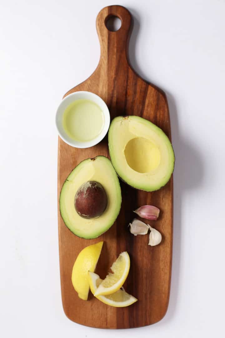 Avocado, lemon, and garlic on a wooden board