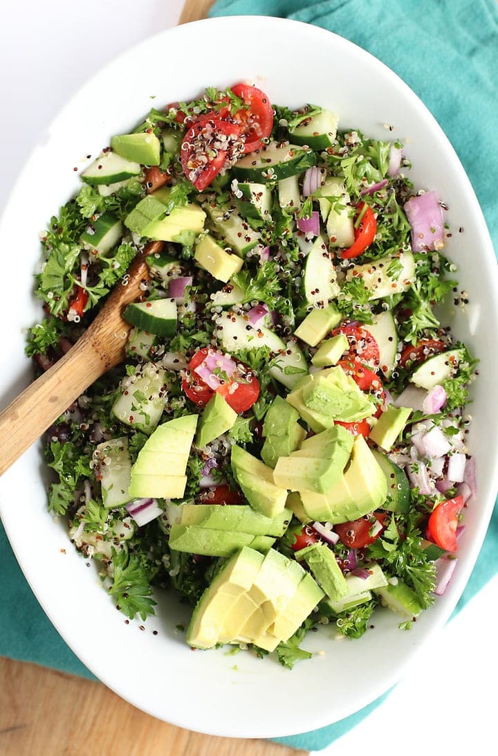 Finished salad in a large white bowl with a wooden spoon