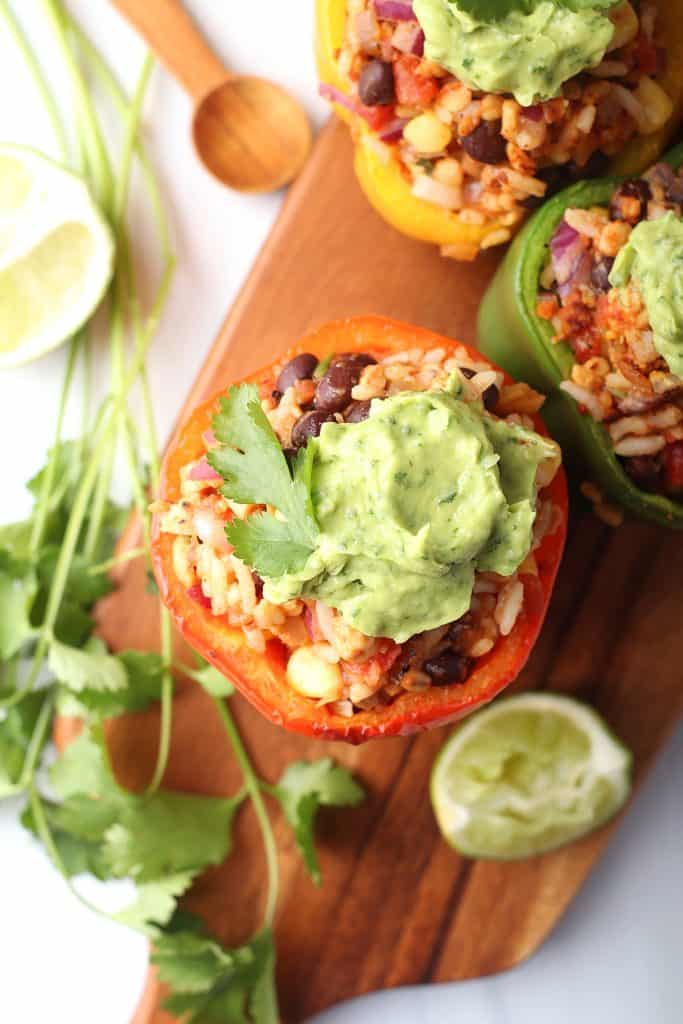 Finished stuffed bell peppers on a wooden platter with cilantro and lime