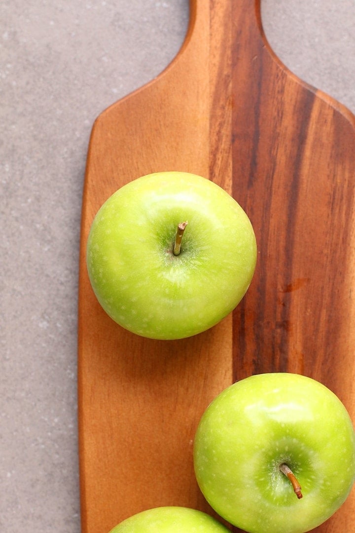 Three Granny Smith Apples on a wooden board