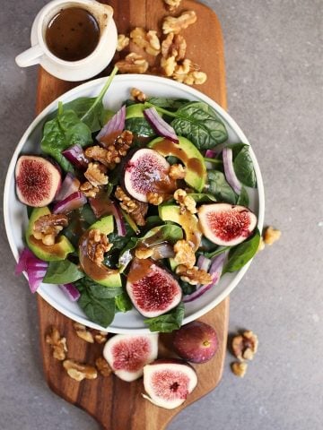 Finished salad on a wooden platter with fresh figs