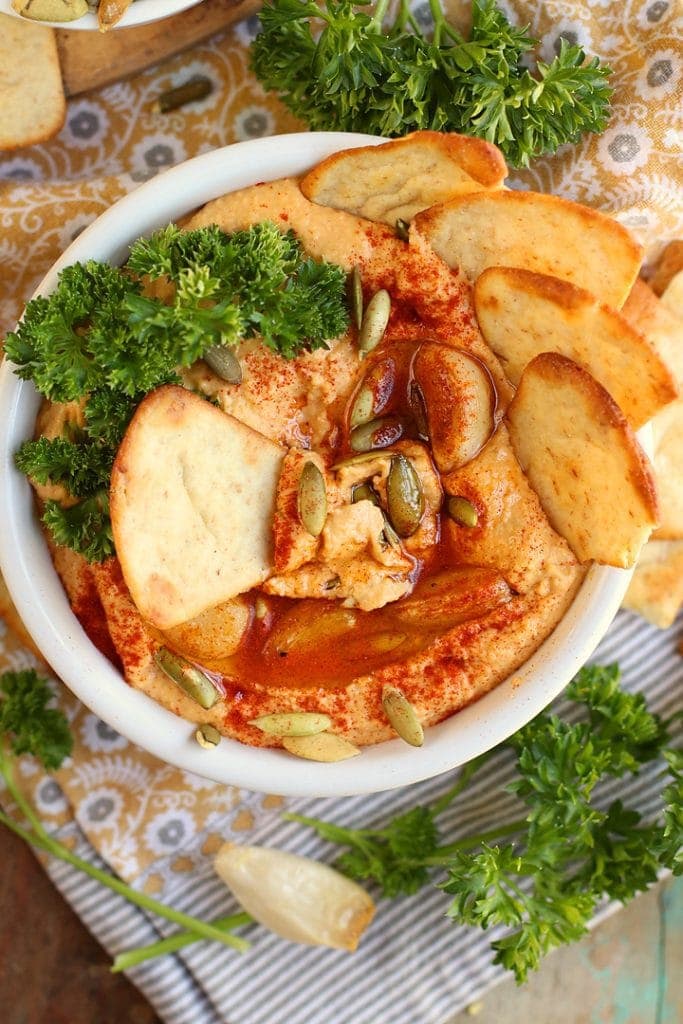 Finished hummus in a white bowl with spices and pita chips