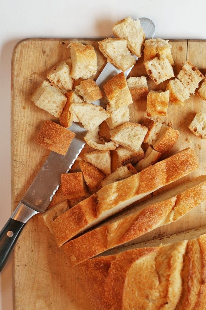 French bread on a cutting board cut into cubes