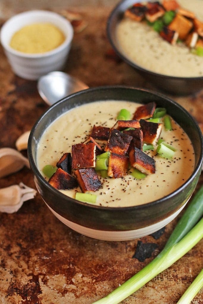 Finished soup in a black and white bowl topped with tofu bacon