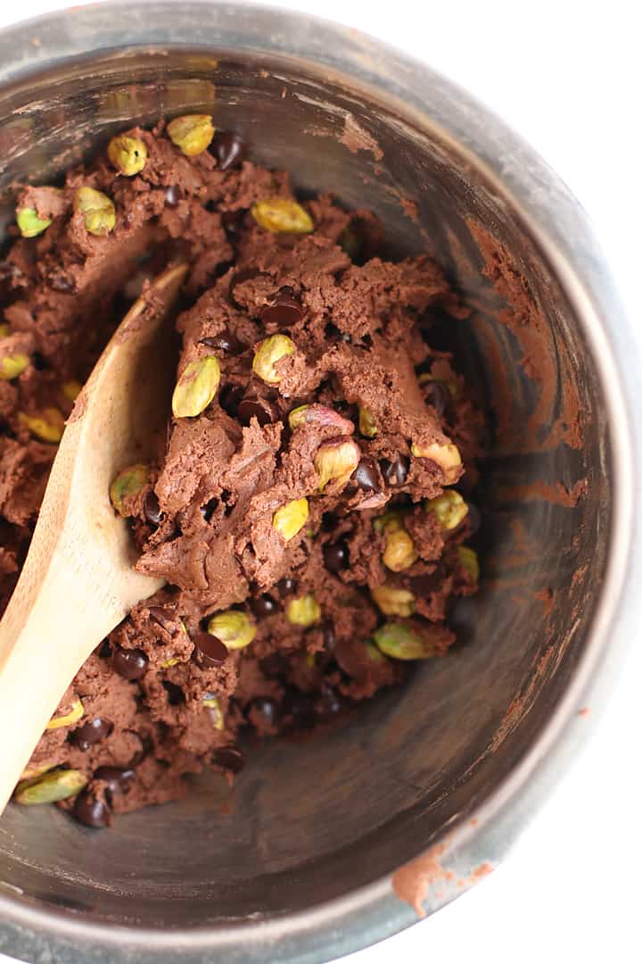 Chocolate cookie dough in a metal bowl with a wooden spoon