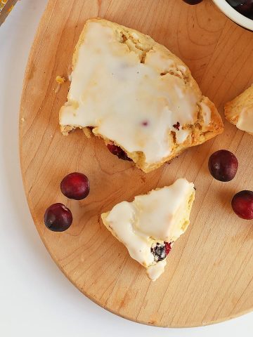 Cranberry Orange Scones broken in half next to fresh cranberries