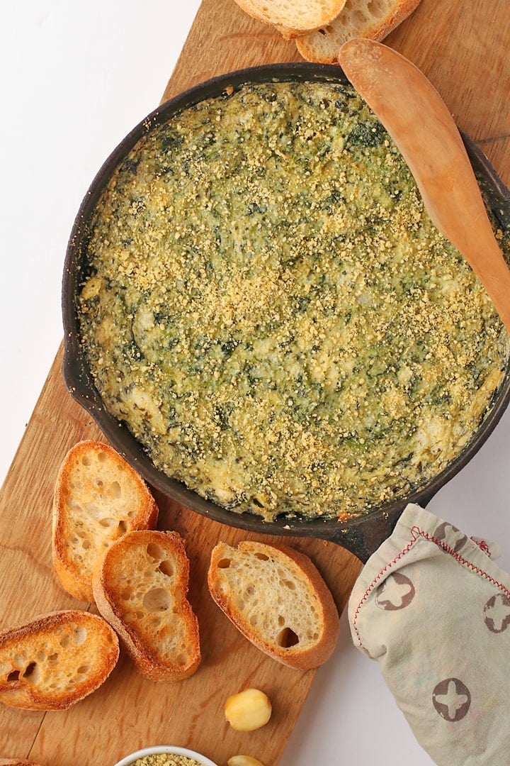 Finished dip in a cast iron skillet with toasted baguette