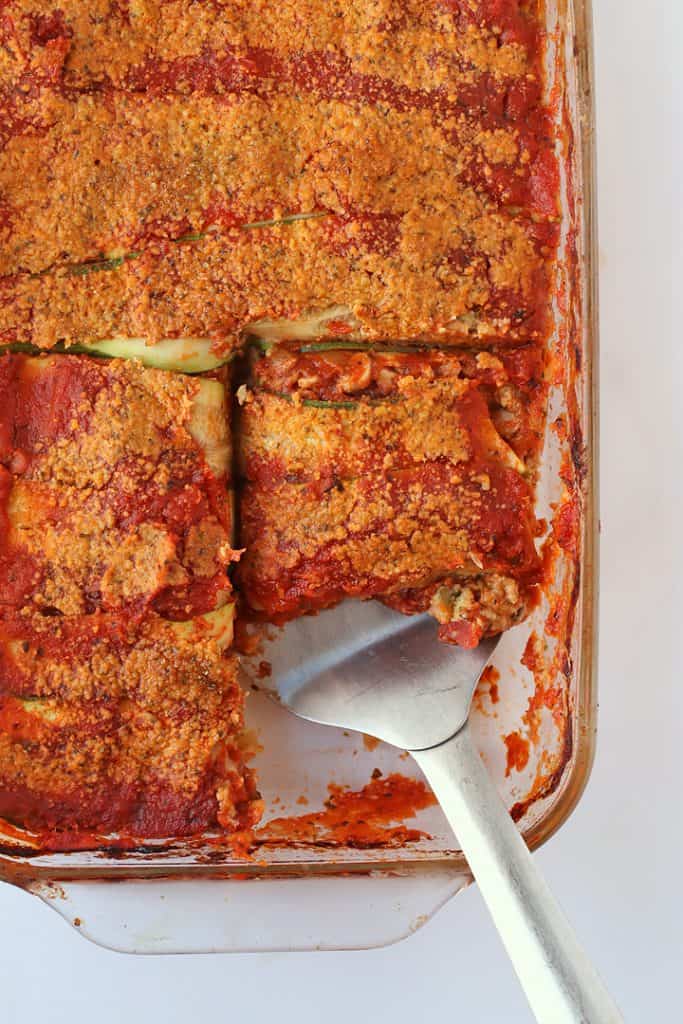 Vegan lasagna in a casserole dish with a metal spatula