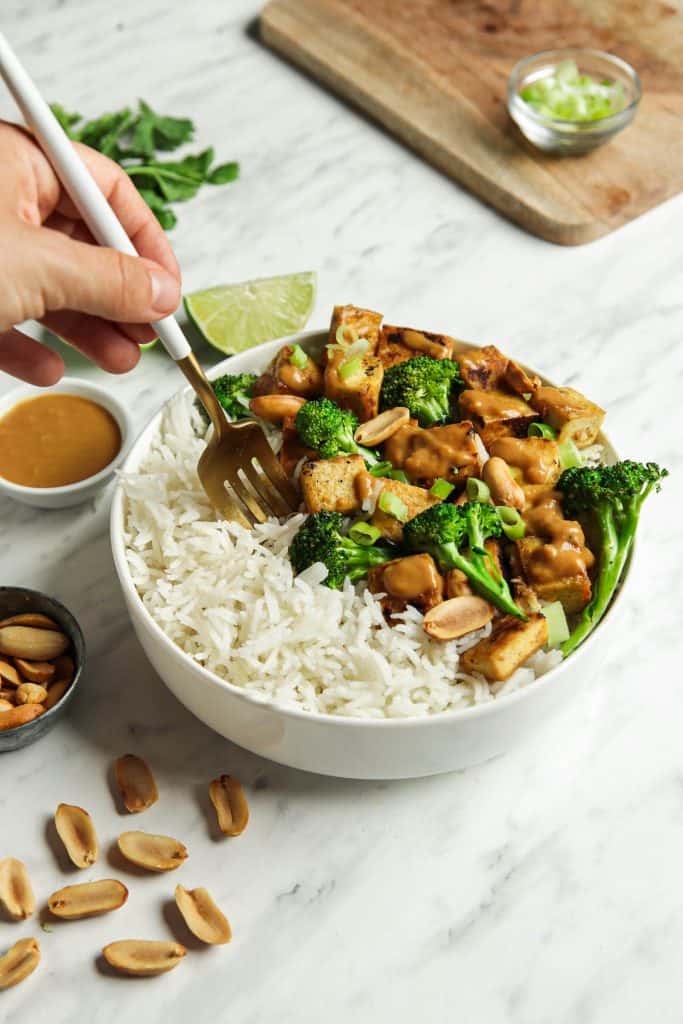 Finished tofu dish served with rice and broccolini in a white bowl. 