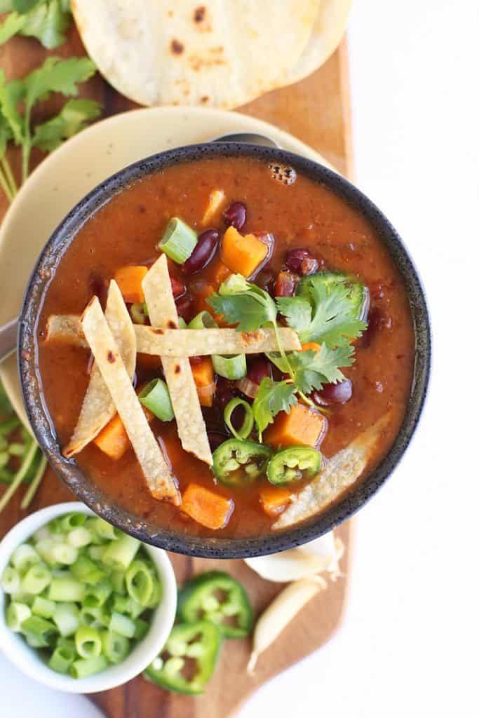 Finished chili in a black bowl with fresh toppings