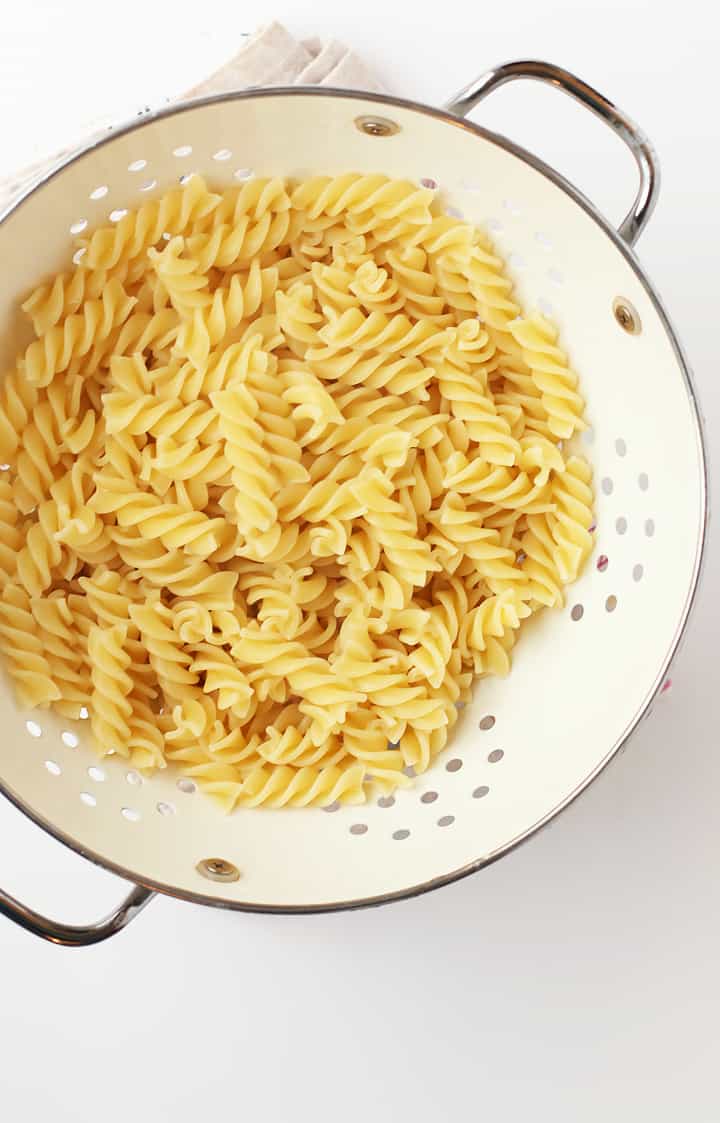 Cooked fusilli pasta in a white cast iron skillet