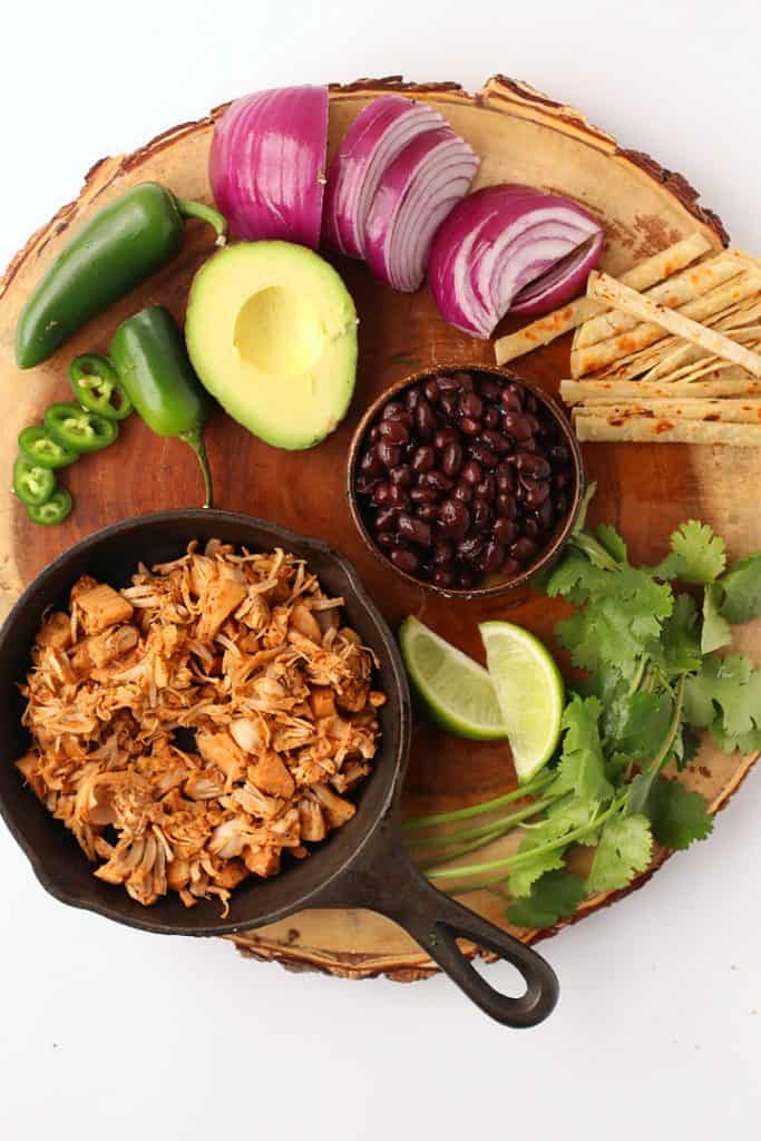 Jackfruit, black beans, avocado, and onions on a wooden platter