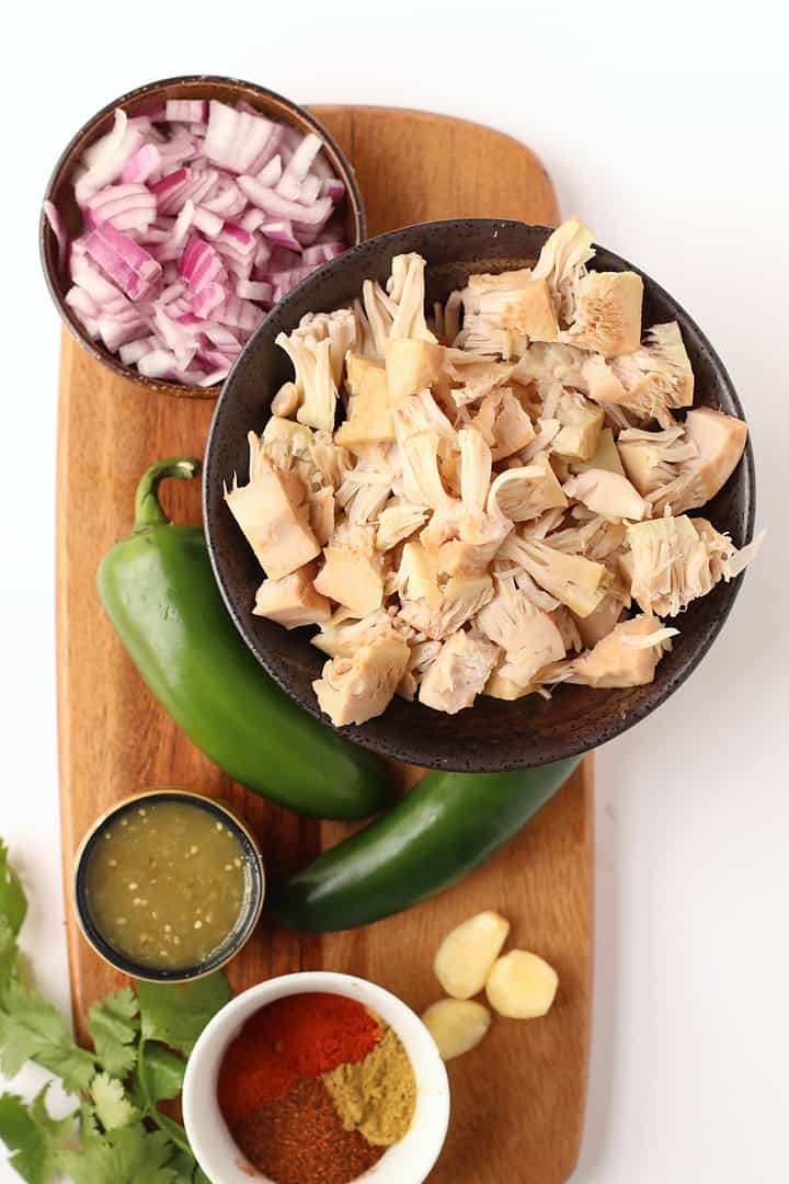 Jackfruit, onions, jalapeños, and salsa verde on a cutting board