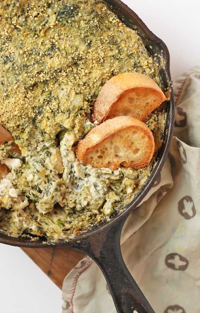 Spinach Artichoke Dip in a cast iron skillet with two slices of bread