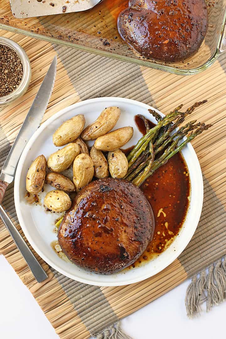 Portobello Steak on a white plate with potatoes and asparagus