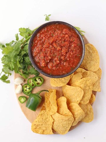 Homemade salsa on a wooden platter with tortilla chips