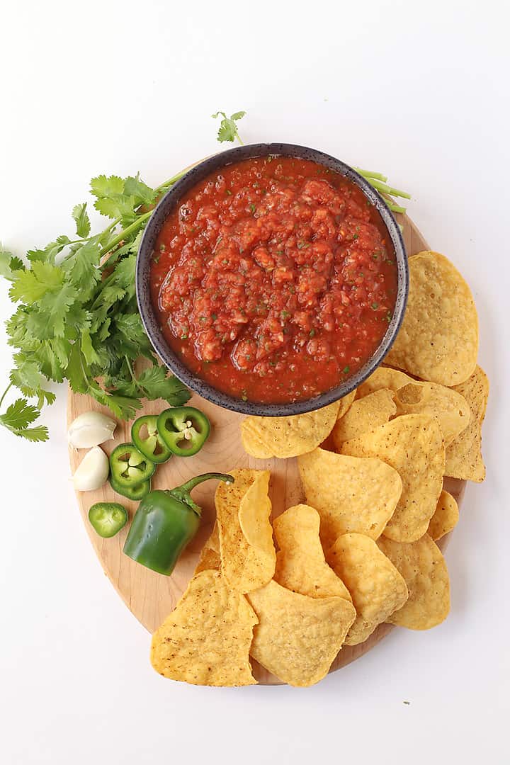 Homemade salsa on a wooden platter with tortilla chips