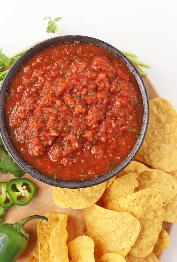 Homemade salsa on a wooden platter with tortilla chips