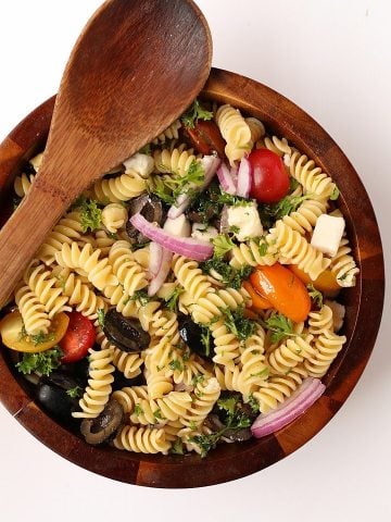 Finished salad in a wooden salad bowl with wooden spoon