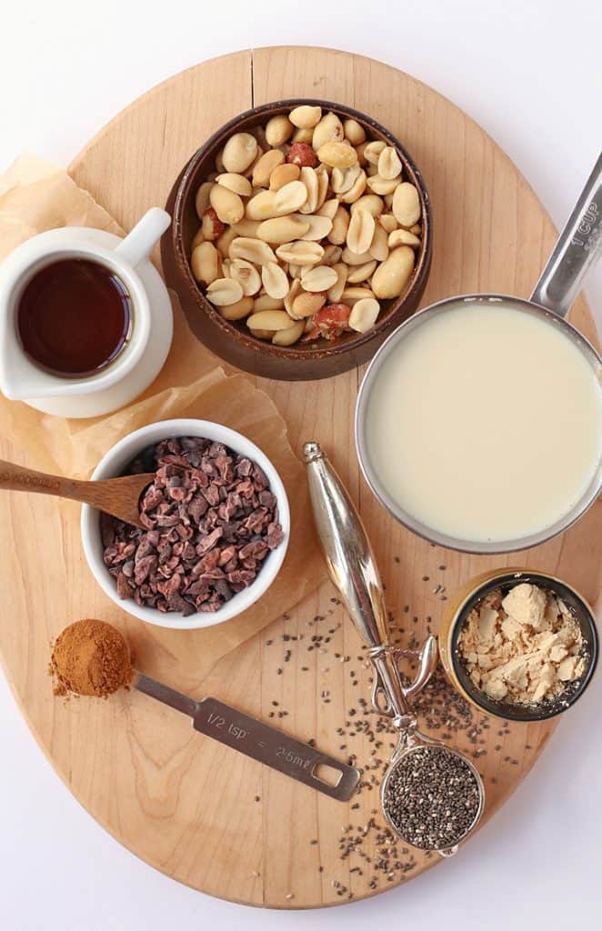 Peanuts, cacao nibs, milk, and chia seeds on a wooden board