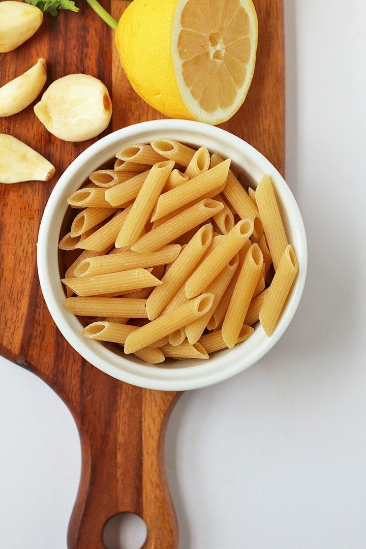 Dried penne pasta in a white bowl