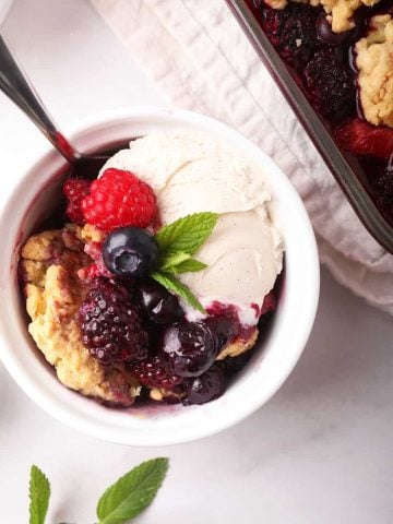 Homemade cobbler in a white bowl with ice cream