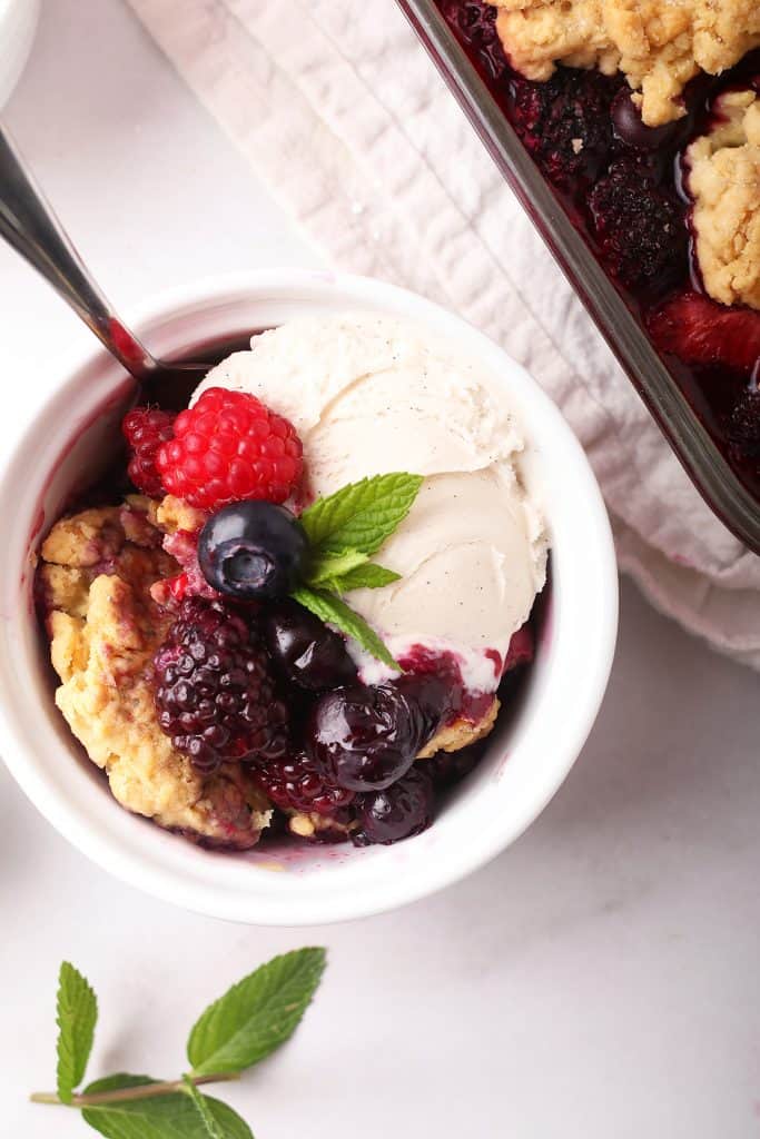 Homemade cobbler in a white bowl with ice cream