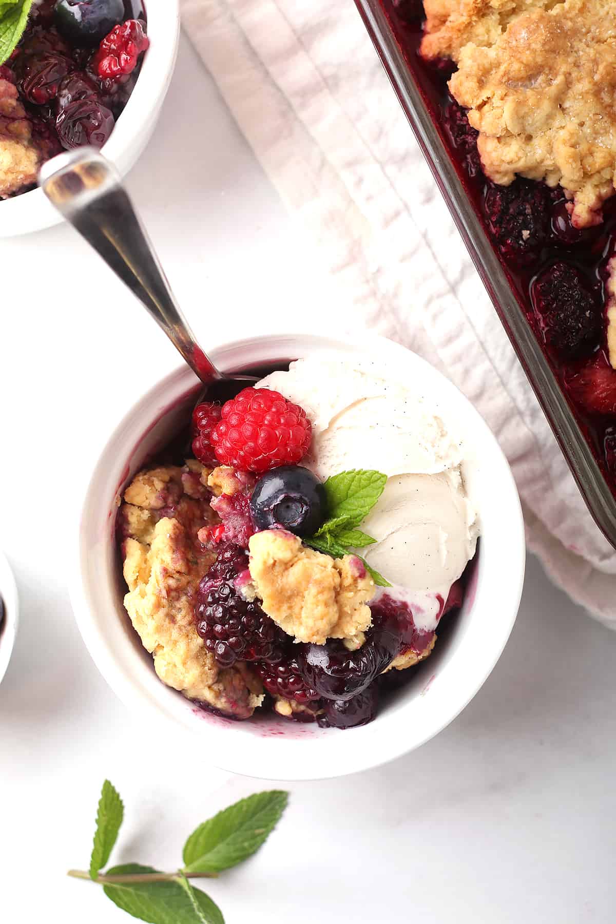 Finished cobbler in a white bowl with ice cream