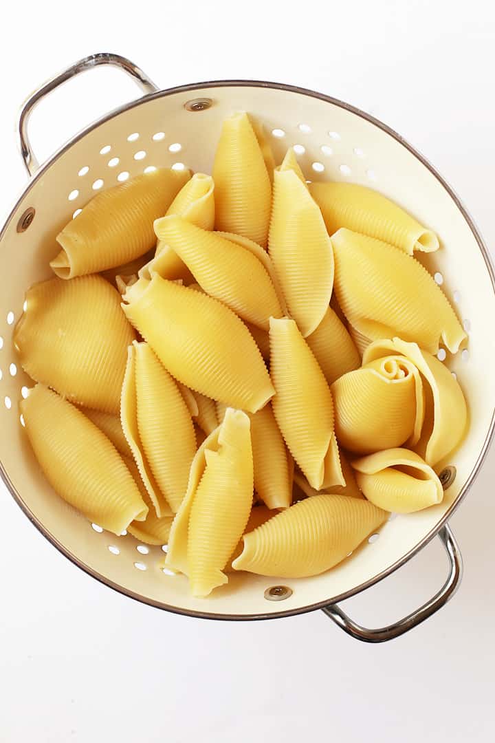 Cooked jumbo shells in a white colander