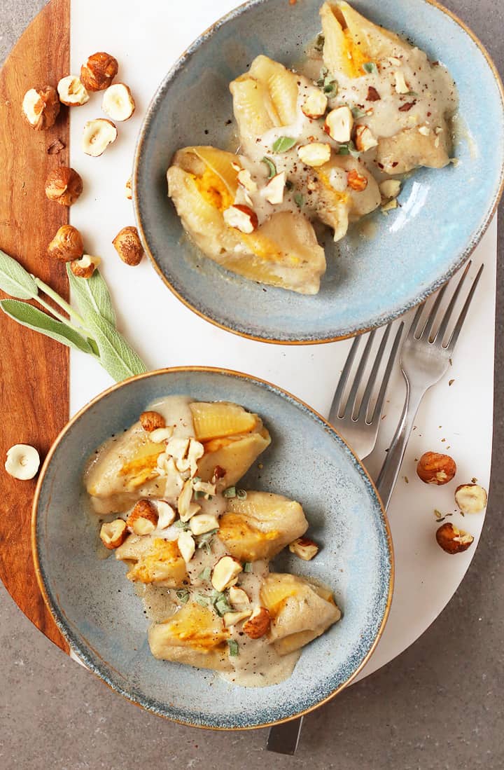 Pumpkin Stuffed Shells in blue bowls on a marble platter. 