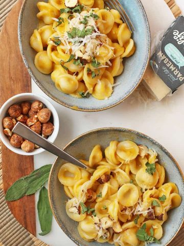 Two bowls of creamy Butternut Squash Pasta with toasted hazelnuts.