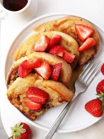 Classic Vegan French Toast with sliced strawberries and maple syrup.