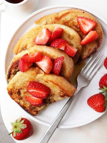 Classic Vegan French Toast with sliced strawberries and maple syrup.